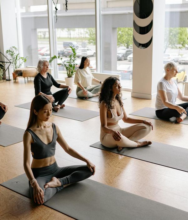 A person sitting in a calm meditative yoga pose in a bright studio.